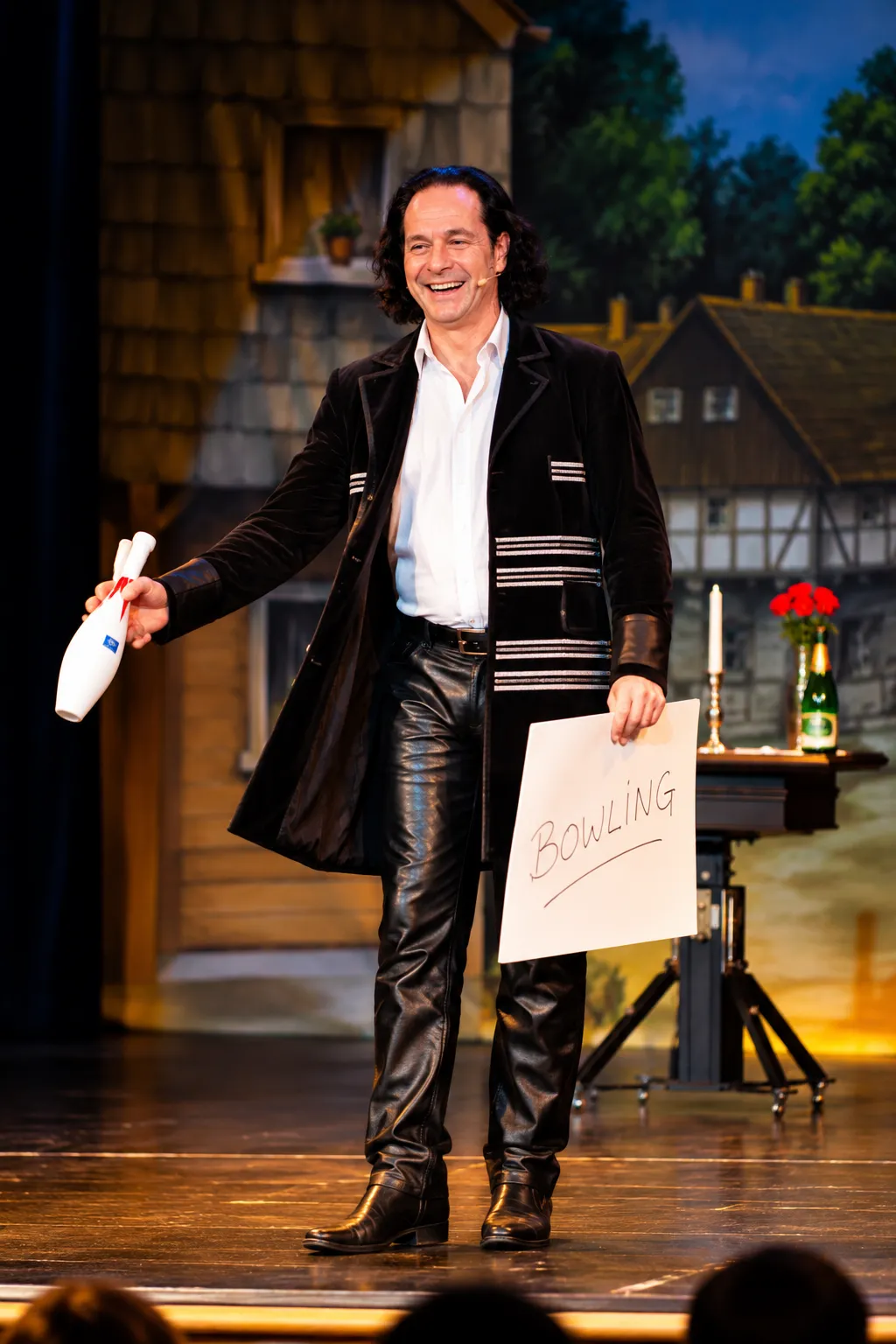 Magier mit Bowling Schild auf der Buehne